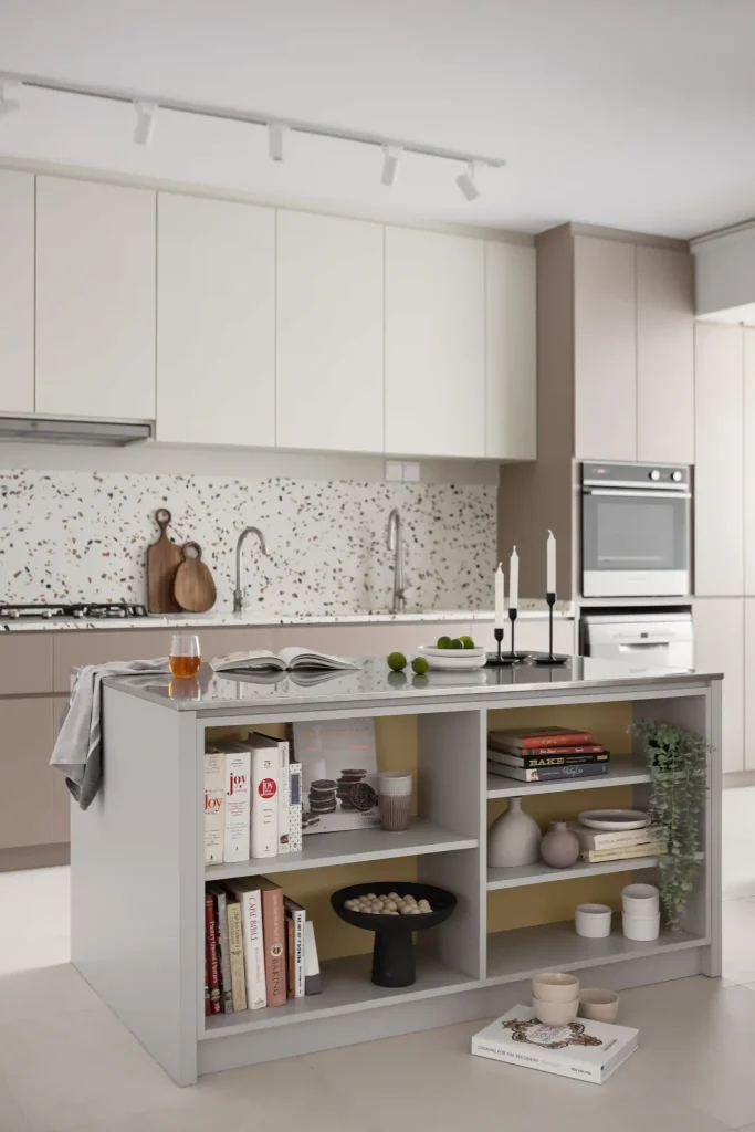 Warm beige kitchen with terrazzo backsplash and open-shelf island styled with cookbooks—modern contemporary interior design in Singapore.