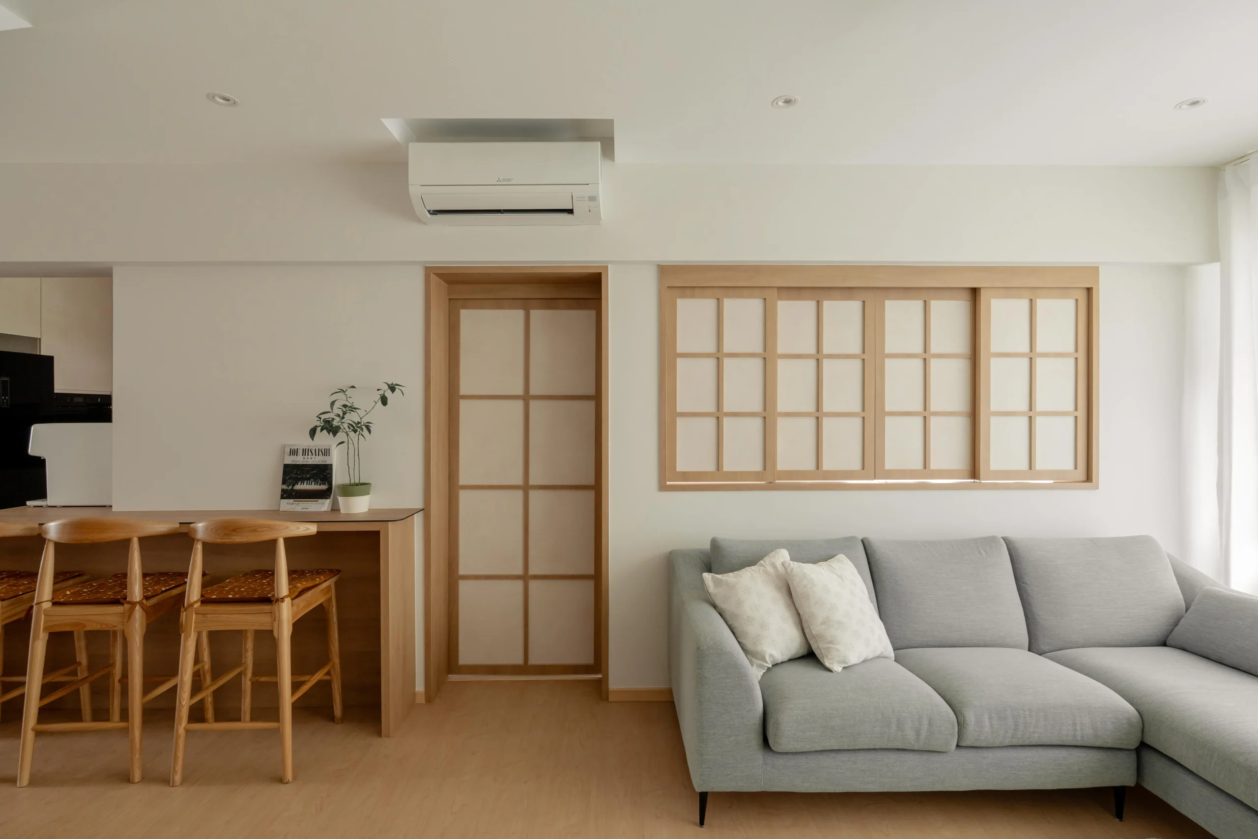 Living room with shoji-style door, two-seat sofa, and light wood flooring.