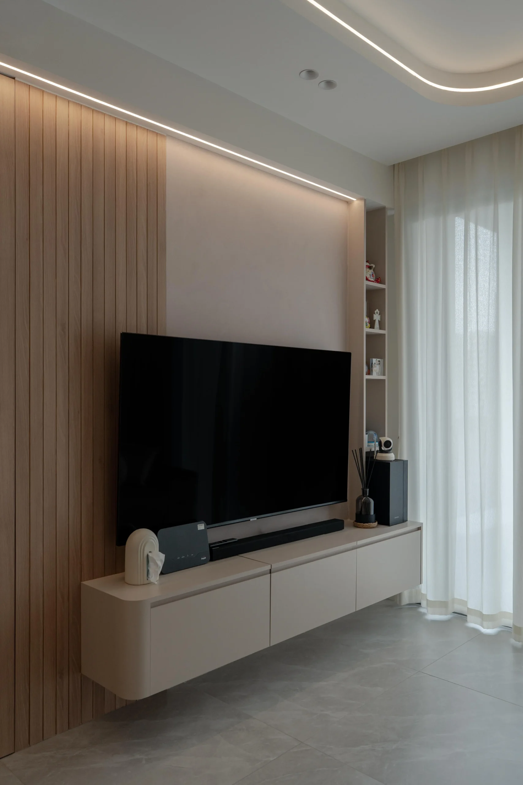 TV wall with fluted wood panels, floating console, and soft cove lighting.