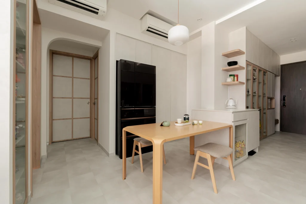 Open dining-kitchen with round wooden table, pendant lamp, black appliance column, and shoji-style doors.